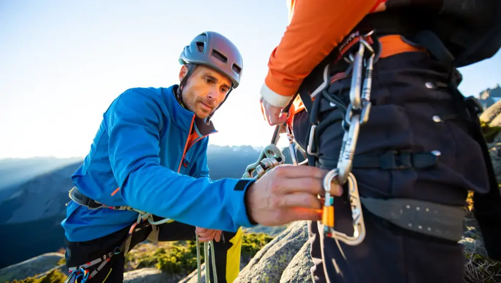 An instructor performing a detailed safety check on a student's harness.