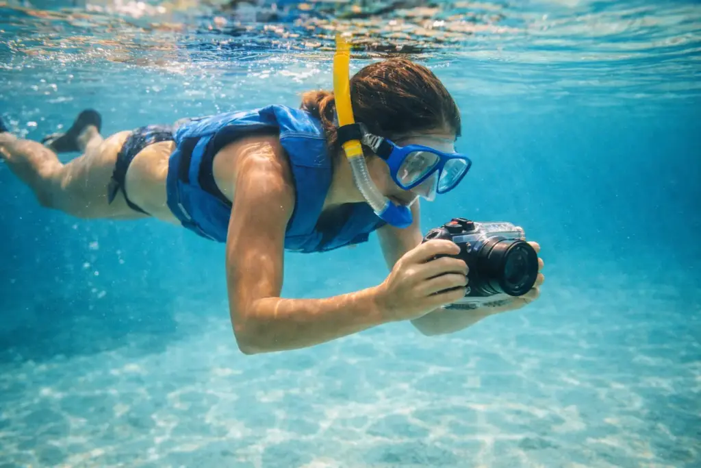  Snorkeler holding an underwater camera housing capturing images of marine life.